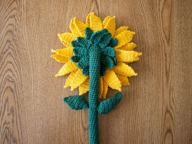 Crochet sunflower with yellow petals and green leaves